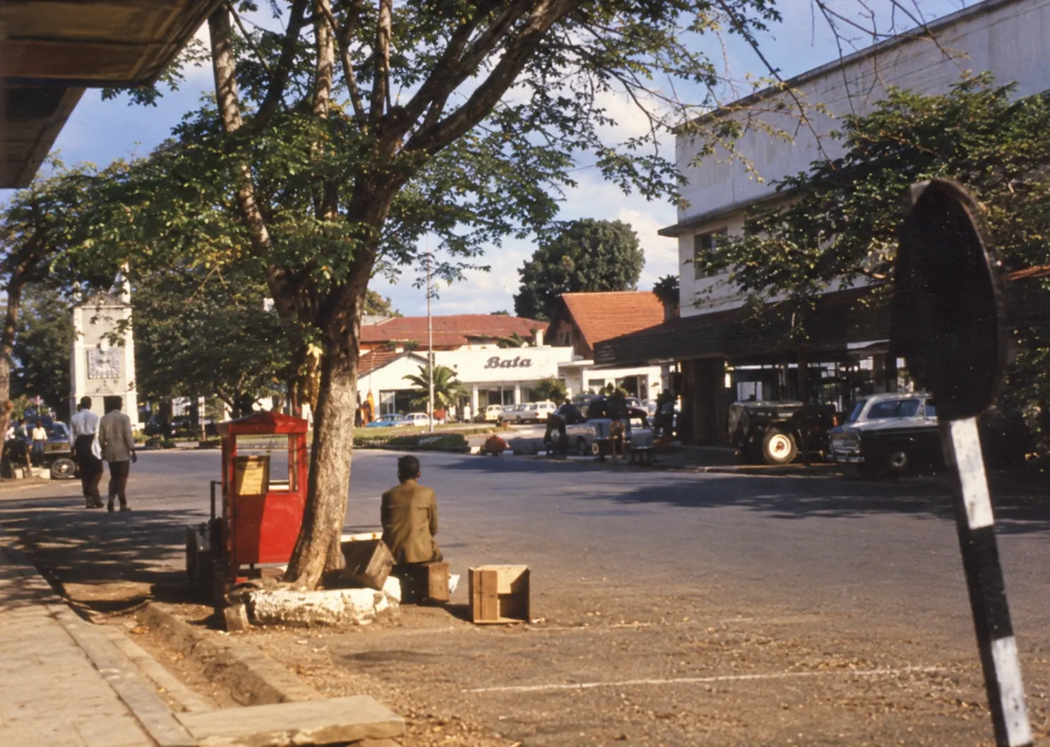 Haile Boutique Hotel at golden hour — a white 1950s house with a wraparound veranda and a tiled roof, palms and a warm brick forecourt.